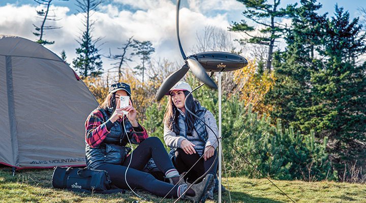 Two people camping and charging their phone with windpower