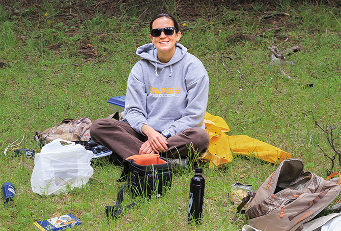 Scientist sitting down smiling and surrounded by her equipment